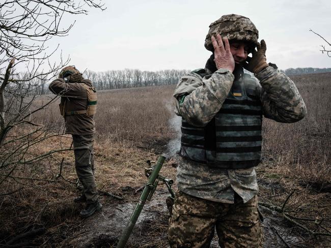 TOPSHOT - Ukrainian servicemen cover their ears as they fire a 60mm mortar toward Russian positions near the frontline in the Donetsk region, on January 31, 2023, amid the Russian invasion of Ukraine. (Photo by YASUYOSHI CHIBA / AFP)