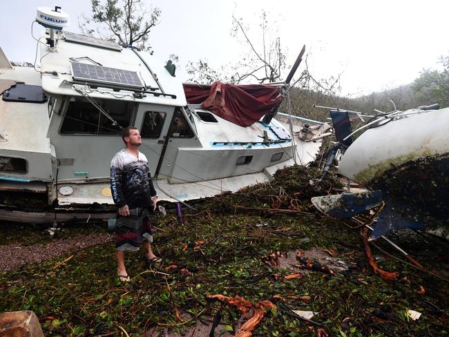 Bradley Mitchell inspects the damage to his uncle's boat after it smashed against the bank at Shute Harbour, Airlie Beach. Picture: Dan Peled/AAP