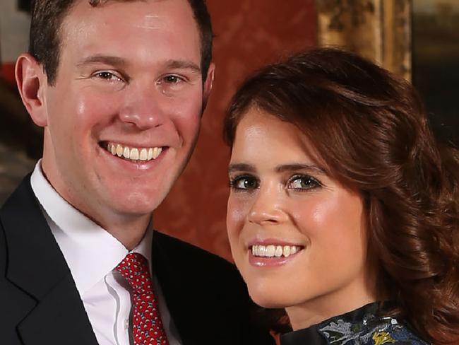 Britain's Princess Eugenie of York (R) poses with her fiance Jack Brooksbank in the Picture Gallery at Buckingham Palace in London on January 22, 2018, after the announcement of their engagement.  Britain's Princess Eugenie of York wears a dress by Erdem, shoes by Jimmy Choo and a ring containing a padparadscha sapphire surrounded by diamonds. Britain's Princess Eugenie of York has got engaged, Buckingham Palace announced January 22, 2018, lining up a second royal wedding this year at the church where Prince Harry will tie the knot.  / AFP PHOTO / POOL / Jonathan Brady