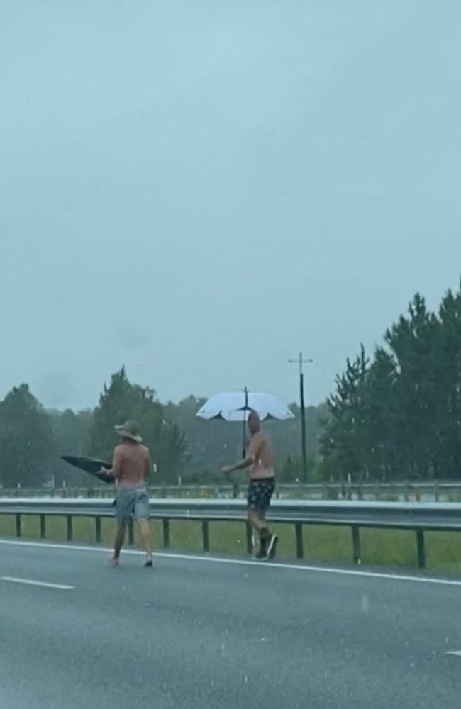 People walking along the Bruce Highway after cars came to a standstill following road closures. Picture: Karen Pereira