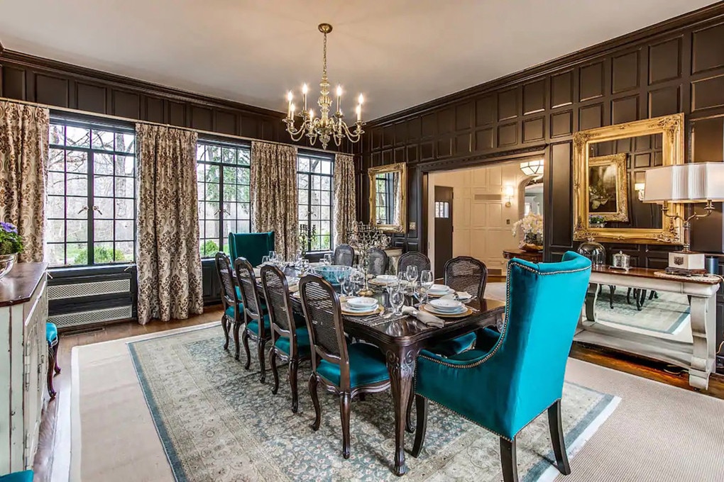 The dark-wood panelled dining room seats 12 with teal suede chairs and large windows. Picture: <a href="http://go.nypost.com/?id=93051X1547088&amp;isjs=1&amp;jv=15.1.0-stackpath&amp;sref=https%3A%2F%2Fnypost.com%2Farticle%2Fjulian-price-house-hillside-hoarders-nightmare%2F&amp;url=https%3A%2F%2Fwww.airbnb.com%2Frooms%2F32381649%3Fsource_impression_id%3Dp3_1618501305_f3IR3CcDqfXkL125%26guests%3D1%26adults%3D1&amp;xguid=4c79130bf437c48d545c287a49d9e4ce&amp;xs=1&amp;xtz=-600&amp;xuuid=d31d49f734323bc25eb43359f37e13fe&amp;xcust=xid%3Afr1620362993480ega&amp;xjsf=other_click__auxclick%20%5B2%5D" title="go.nypost.com">Airbnb</a>