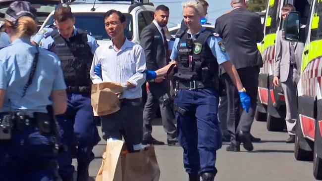 Mu Rong Hong, pictured in handcuffs and his hands bagged after stabbing his wife to death in Berala in November 2019. Picture: TNV