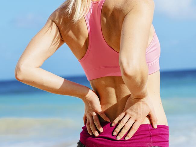 Back Pain. Athletic fitness woman rubbing the muscles of her lower back. Sports exercising injury. Istockphoto pic