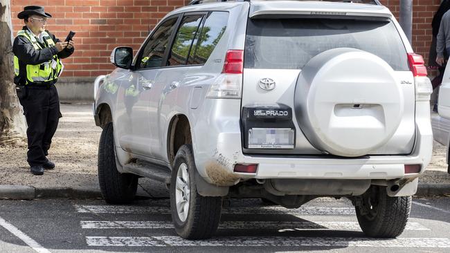 A parking inspector writes up a ticket for a four-wheel drive parked on a pedestrian crossing near the zoo.