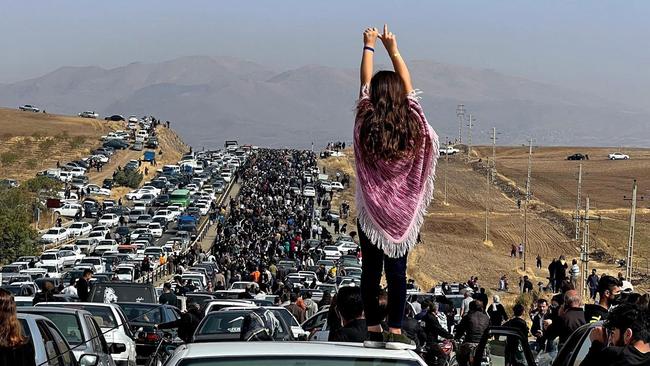 An unveiled woman defies the regime as thousands in October 22 make their way towards Aichi cemetery in Saqez, Mahsa Amini's home town, to mark 40 days since her death. Picture: AFP