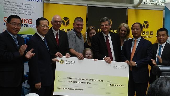 Seven-year-old Erin Hutchinson accepts the giant cheque from Yuhu Group Huang Xiangmo (second from right).