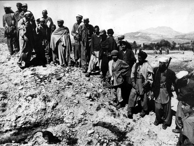 Mujahideen look in a shallow grave at the bodies of three Afghanis, found guilty after a rapid trial, of collaborating with the occupying Russian forces in 1981.