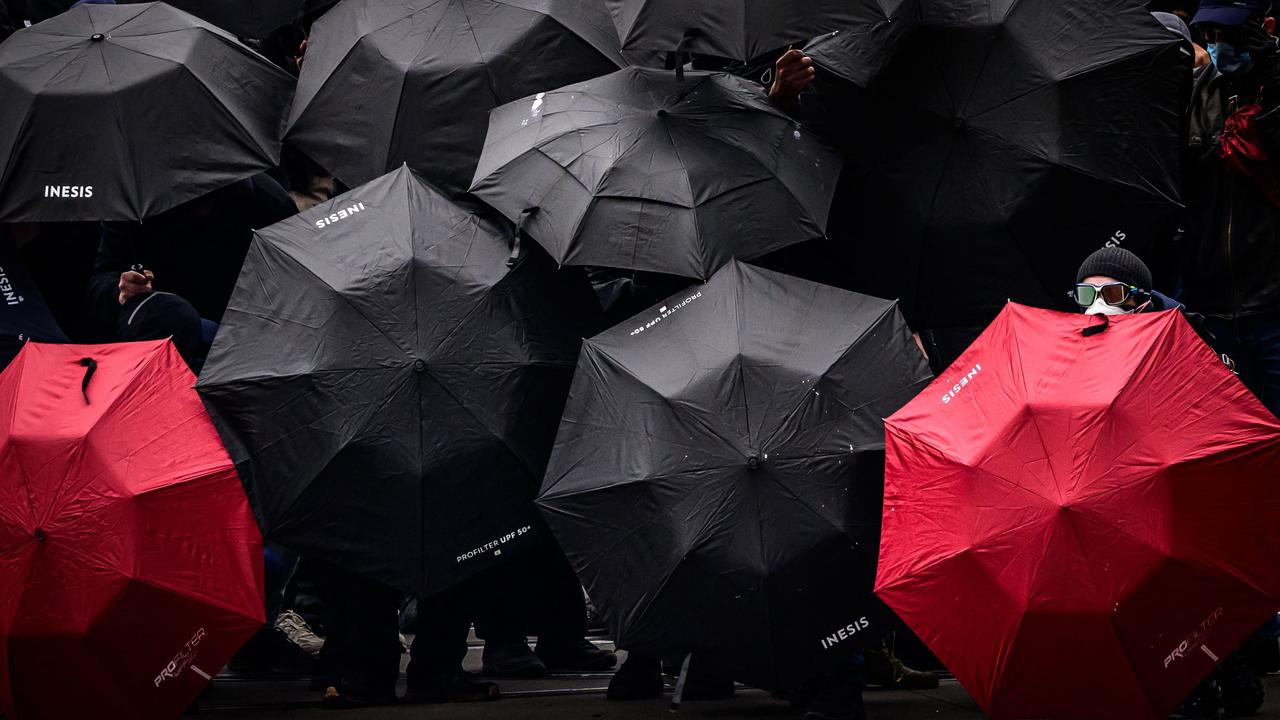 Protesters shield themselves with umbrellas during altercations with French anti-riot police during a May Day rally in Nantes. Picture: Loic Venance/AFP