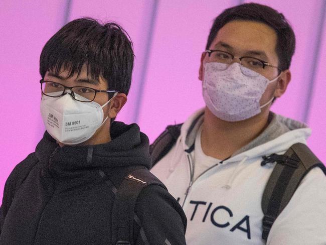 Passengers wear face masks to protect against the spread of the Coronavirus as they arrive on a flight from Asia at Los Angeles International Airport, California, on January 29, 2020. - A new virus that has killed more than one hundred people, infected thousands and has already reached the US could mutate and spread, China warned, as authorities urged people to steer clear of Wuhan, the city at the heart of the outbreak. (Photo by Mark RALSTON / AFP)