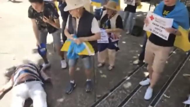 A still from a video uploaded to Twitter shows the moment an elderly man falls down stairs during a pro-Ukraine rally near Town Hall in Sydney on December 13 2022.