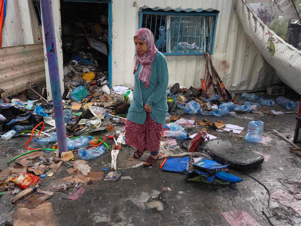 A Palestinian woman inspects the debris of a container at an UNRWA school used to shelter displaced people, after it was hit in Israeli bombardment on Nusseirat in the central Gaza Strip. Picture: AFP