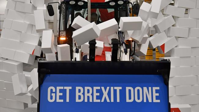 Boris Johnson drives a JCB through a symbolic wall with the Conservative Party slogan 'Get Brexit Done' in the digger bucket. Picture: AP.