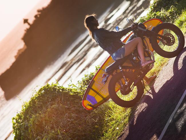 SUNDAY ESCAPE. INTERNATIONAL DRIVING PERMITS. Travellers often find themselves in trouble when they ride a motorbike without a licence - or a helmet. Girl on motorcycle with surfboard at Bali. Picture: iStock