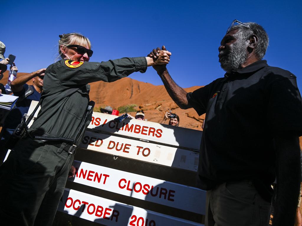 Uluru-Kata Tjuta Ranger Lynda Wright (left) and Chair of the Uluru-Kata Tjuta Council Sidney James shake hands after the new sign showing the closure is installed. Picture: AAP Image/Lukas Coch