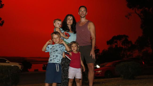 A German family awaits evacuation from the Mallacoota fires in Victoria on Saturday. They are Kai and Deniz Kirschbaum with their three children sheltering at the community centre, left to right, Nuri 5, Kian 1, and Sanira, 3. Picture: David Caird