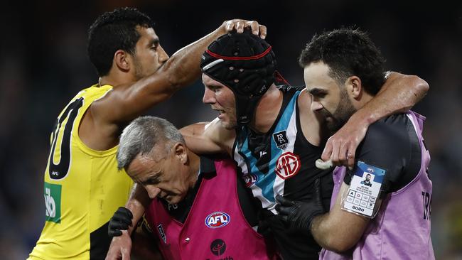 Brad Ebert is helped from the field in what will be his last AFL game.