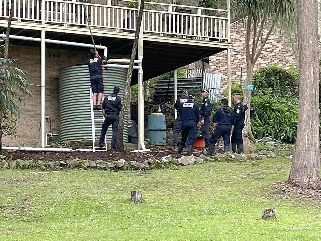 Police look at a water tank at the house William Tyrrell went missing from near Kendall.