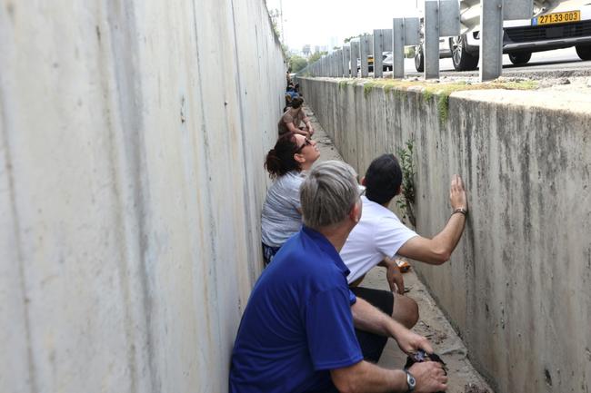 People leave their vehicles to take cover during a rocket attack along a main road in Tel Aviv