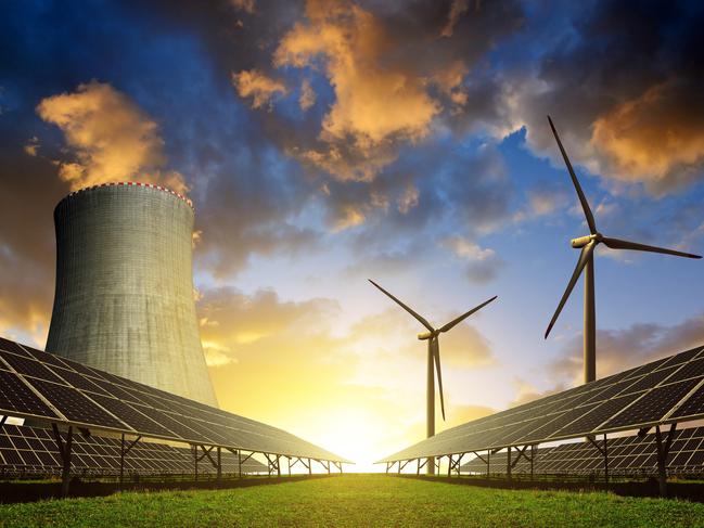 Solar energy panels before a nuclear power plant and wind turbines at sunset