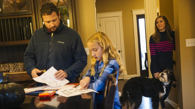 Elizabeth Moore, 43, and her dog Brandy look on as her husband Ryan Moore, 43, helps their daughter Amelia, 10, with her school work at home. Picture: Taylor Glascock/ The Wall Street Journal