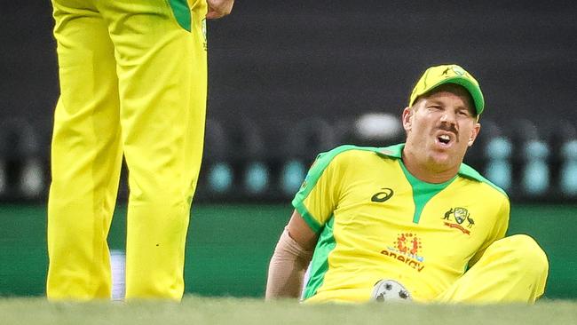 David Warner winces after suffering an injury in the field against India at the SCG on Sunday Picture: AFP