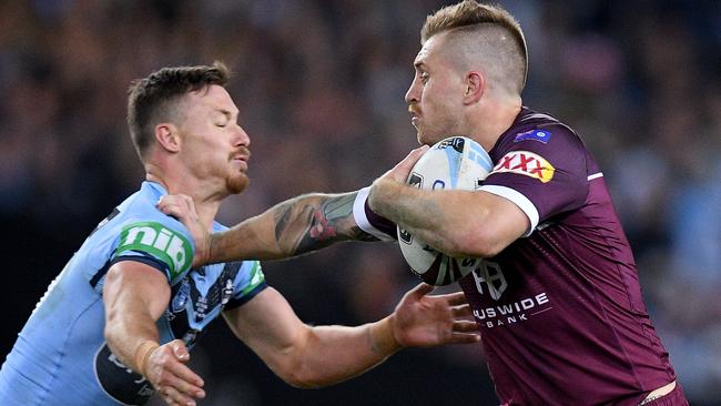 Maroons fullback Cameron Munster fends off a tackle from Blues hooker Damien Cook. Picture: AAP