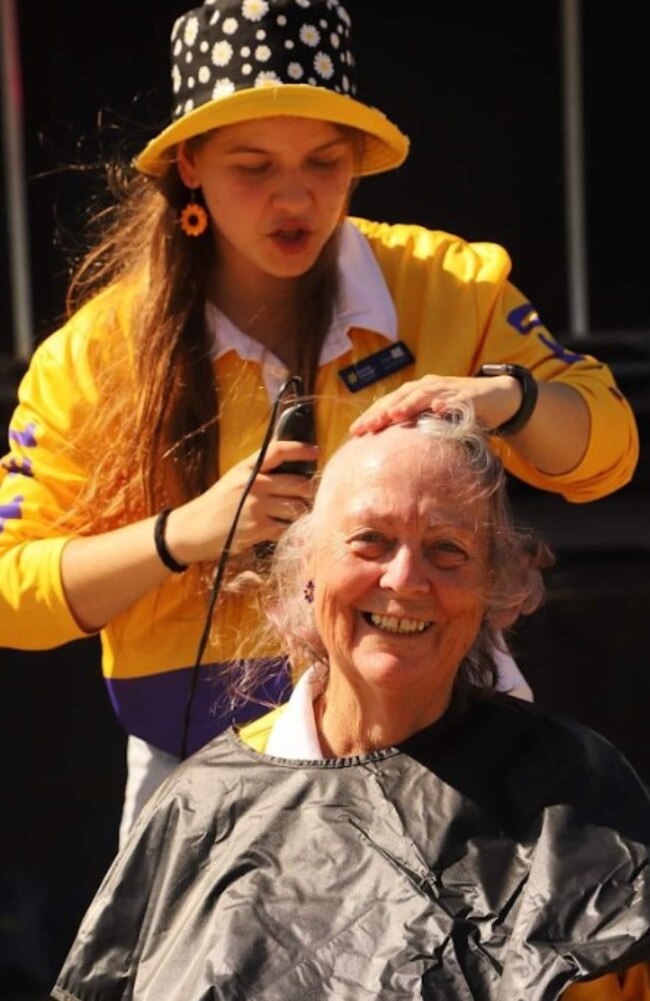 Dani Robert (back) shaves a volunteers head as part of her time spent with Shave for a Cure.