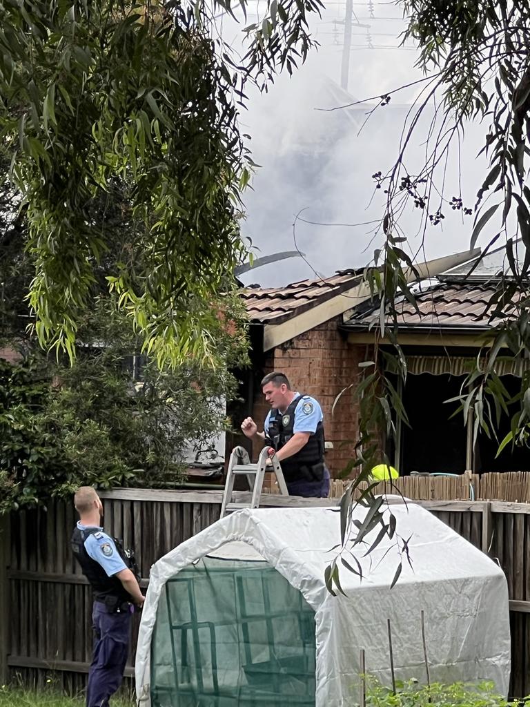 Police climb a ladder to reach the woman’s house.