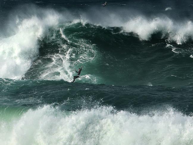 A couple of guys take turns riding a jet ski while the other surfs the huge swell .picture John Grainger