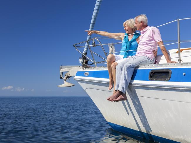 Quest - Active Living - March 2019 - A happy senior couple sitting on the side of a sail boat on a calm blue sea looking and pointing to a clear horizon