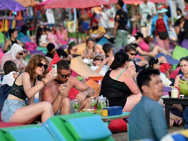 Foreign tourists enjoy their holiday at Kuta beach near Denpasar, Indonesia's Bali island on May 31, 2025. (Photo by SONNY TUMBELAKA / AFP)