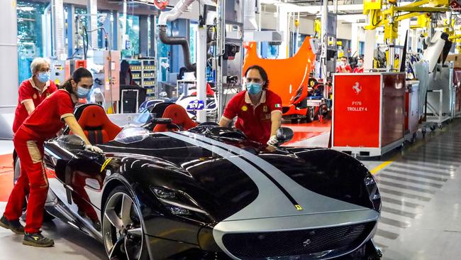 Workers push a Ferrari Monza SP2 V12 at the Maranello assembly line. Picture: AFP.