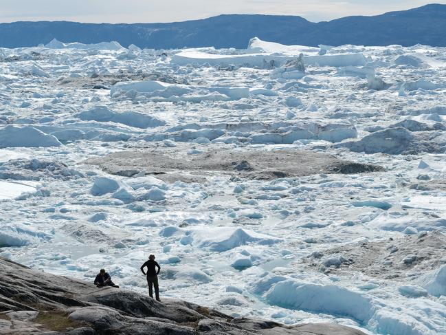 ILULISSAT, GREENLAND - JULY 30: Visitors look out onto free-floating ice jammed into the Ilulissat Icefjord during unseasonably warm weather on July 30, 2019 near Ilulissat, Greenland. The Sahara heat wave that recently sent temperatures to record levels in parts of Europe is arriving in Greenland. Climate change is having a profound effect in Greenland, where over the last several decades summers have become longer and the rate that glaciers and the Greenland ice cap are retreating has accelerated.   (Photo by Sean Gallup/Getty Images)