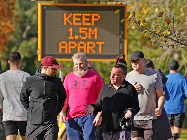 People walk along the Tan Track near a sign with a message to help slow the spread of the coronavirus (COVID-19) disease in Melbourne, Sunday, May 24, 2020.  Under an easing of coronavirus restrictions, Victorians will be allowed to have up to 20 people in their homes and stay overnight at tourist accommodation from June 1.  (AAP Image/Scott Barbour) NO ARCHIVIN2