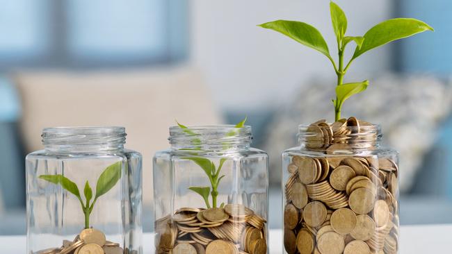 Green plant growing in glass jar with coins, superannuation generic