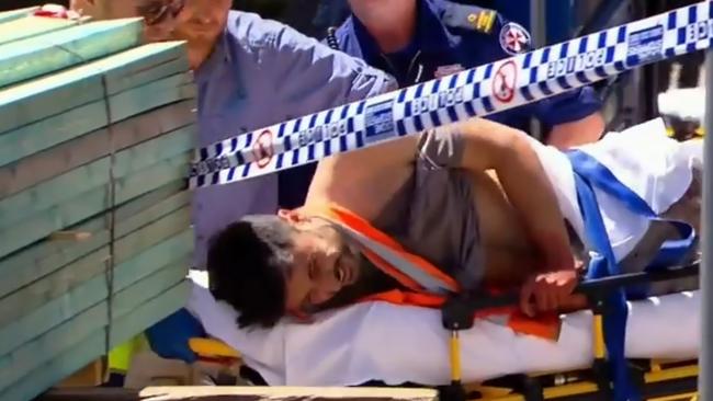 Antony Metledge writes in pain as he is taken by paramedics with a knife still in his back. Picture: Nine News