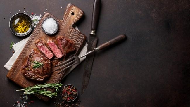 Grilled ribeye beef steak, herbs and spices. Top view with copy space for your text