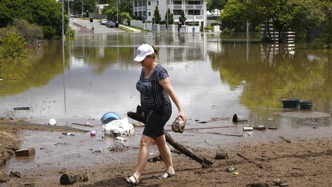 A woman clears debris at a flooded road in Fairfield. Picture: Tertius Pickard