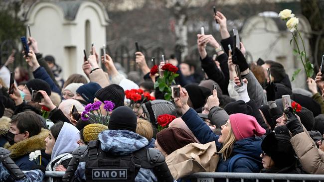 Mourners react as the hearse leaves the church; riot police officers stand on guard. Picture: AFP