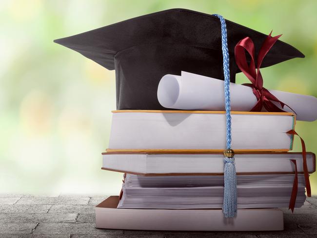 Graduation hat with degree paper on a stack of book against blurred background