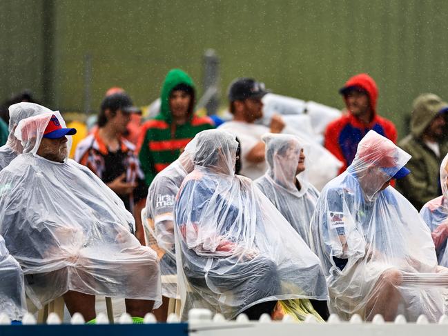 Spectators in rain jackets and ponchos are seen during the round 10 NRL match between Wests Tigers and Newcastle Knights.