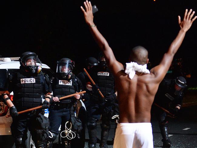 A man raises his arms in front of officers in Charlotte after a night of violent protests. Picture: Jeff Siner/The Charlotte Observer via AP