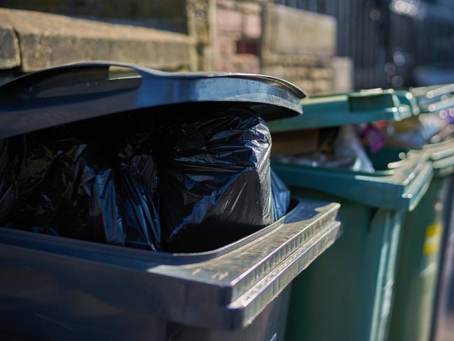 Gray and green garbage cans overfilled with domestic refuse