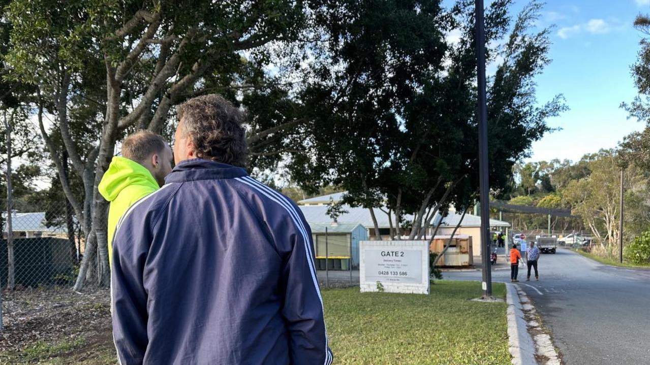 Workers are waiting to pick up their tools outside the gates of the Palmer Coolum Resort in Yaroomba.