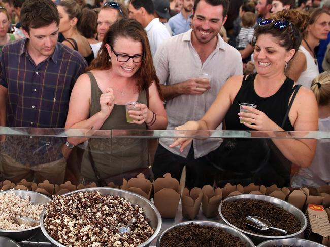 This photo taken on January 28, 2017 shows customers looking at different kinds of insects at a stall in Sydney. Roasted cockroach, honey-flavoured ants, mealworm and chocolate coated popcorn are now available to try and buy -- and while the cuisine remains a novelty, there are signs it is growing in popularity. / AFP PHOTO / ANDREW MURRAY / TO GO WITH Australia-lifestyle-food-bugs-insects,FEATURE by Daniel DE CARTERET