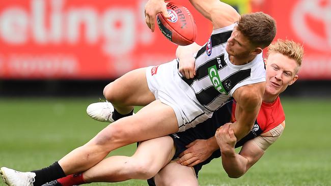 Taylor Adams of the Magpies is tackled by Clayton Oliver