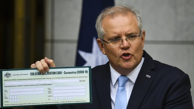 Australian Prime Minister Scott Morrison holds up a Coronavirus Isolation Declaration Card as he unveils new restrictions on those entering the country. Picture: AAP Image/Lukas Coch.