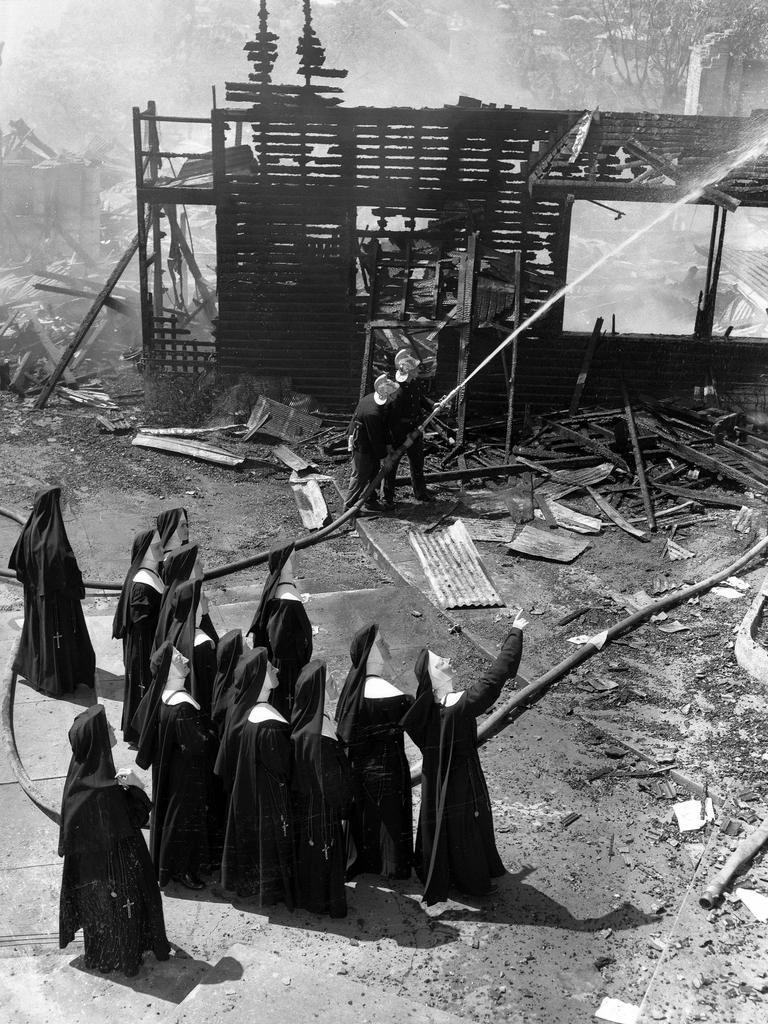 The nuns of Lourdes Hill Convent survey damage caused by a fire as firemen dampen it down, in 1960. Picture: Al Pascoe Snr