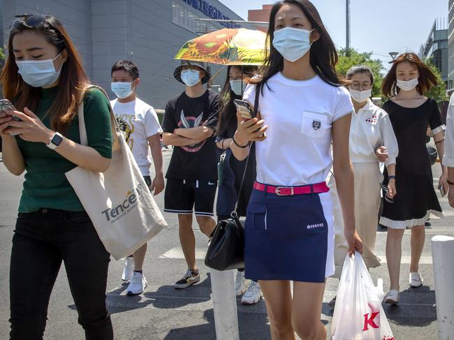 People wear face masks to protect against the coronavirus as they walk across an intersection in Beijing, Friday, June 5, 2020. China on Friday reported five new confirmed coronavirus cases, all of them brought by Chinese citizens from outside the country. (AP Photo/Mark Schiefelbein)