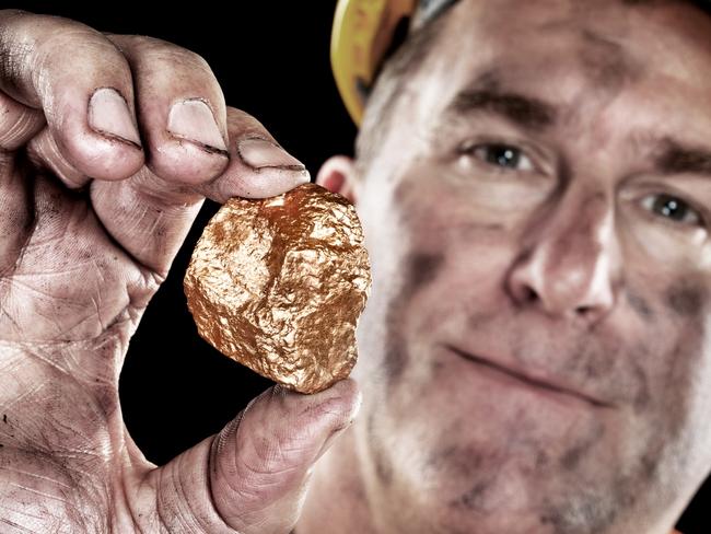 A gold miner shows a golden hugget freshly excavated from a mine.